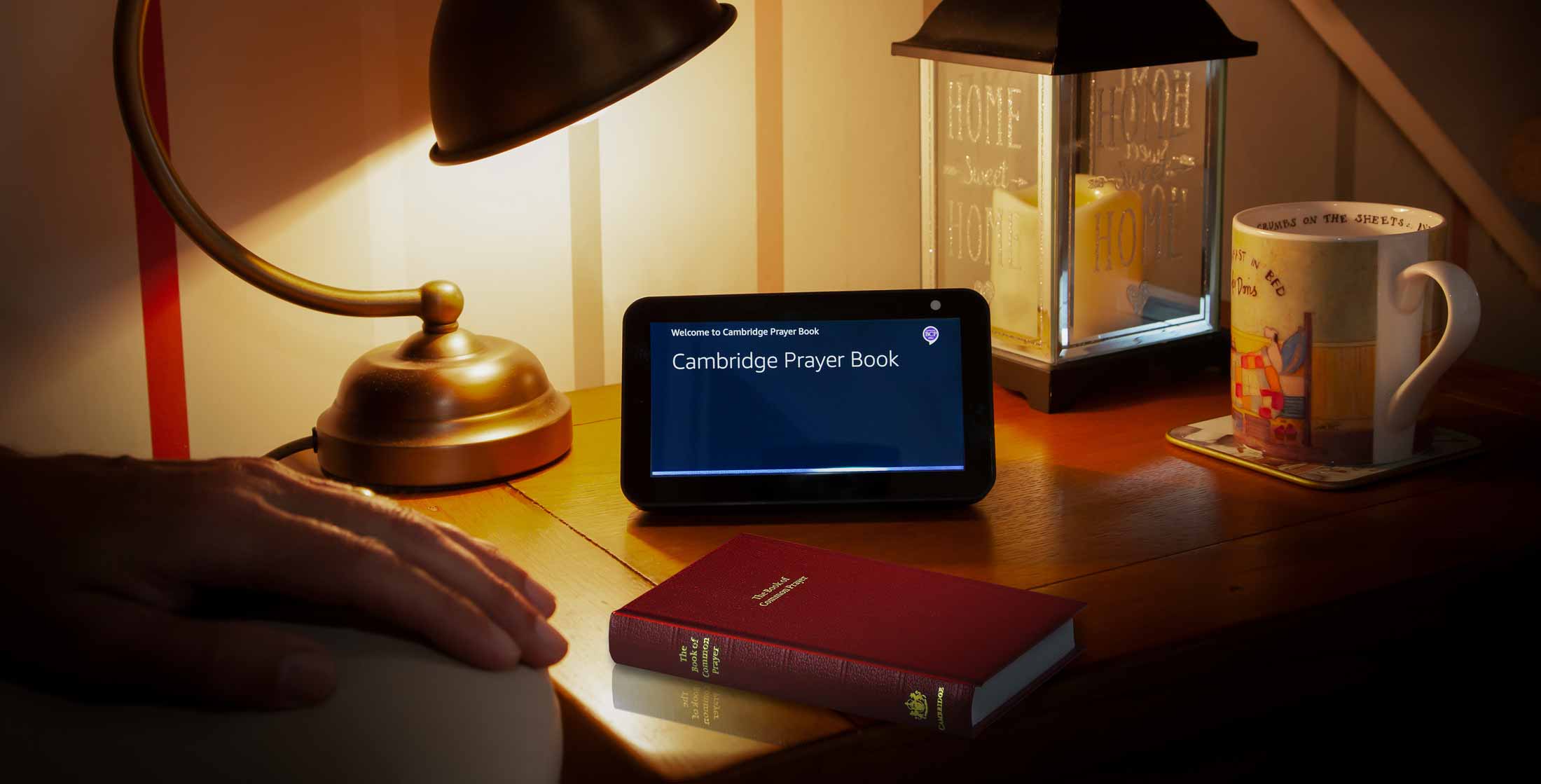 Amazon echo and Book of Common Prayer on a table light by a lamp