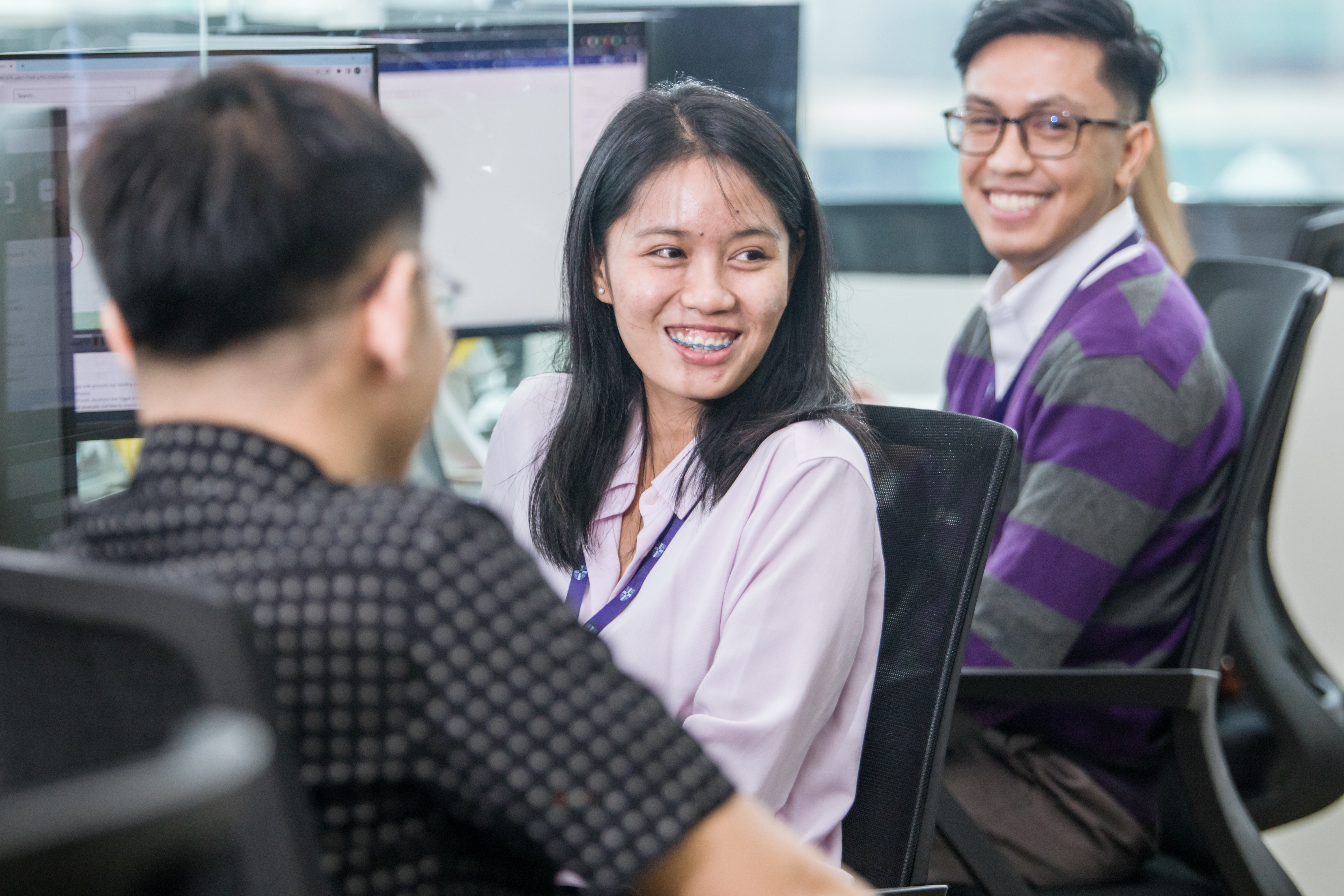 three colleagues sat at desks smiling