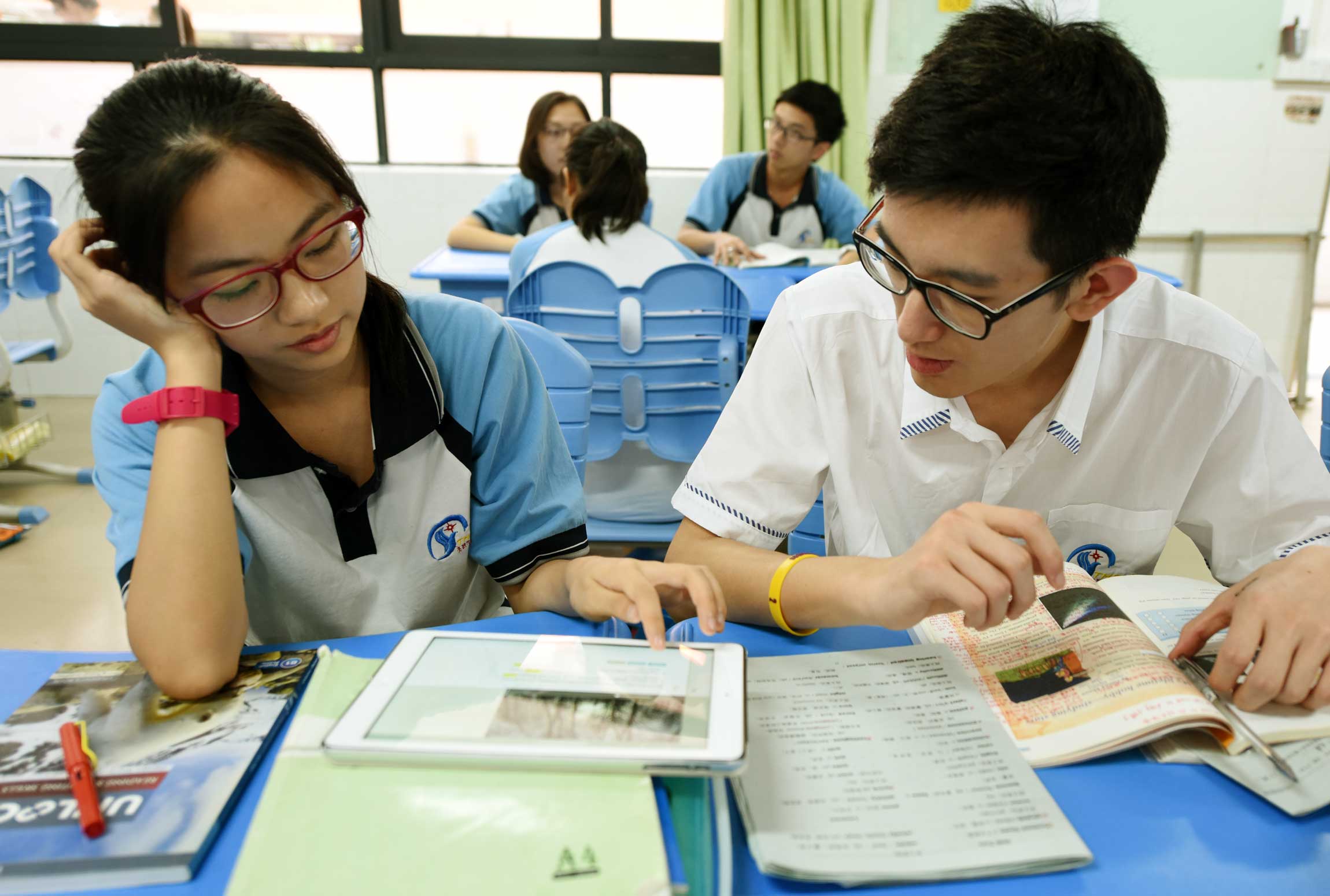 Female and male school children learning English in their classroom.