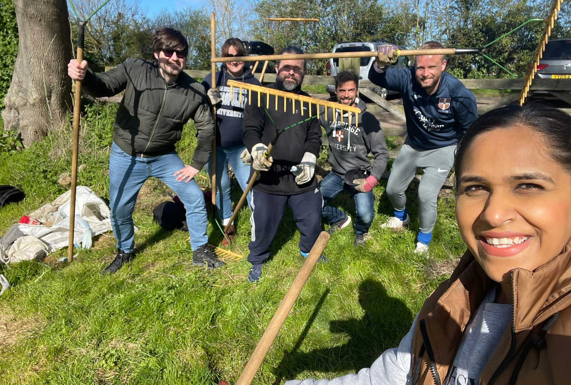 Cambridge colleagues in a field with rakes and spades.