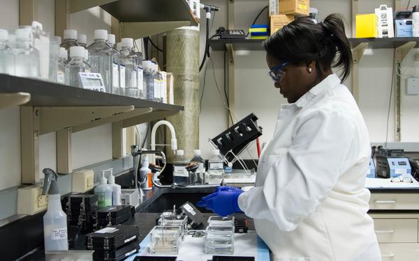 woman wearing white lab coat and blue gloves working in a lab