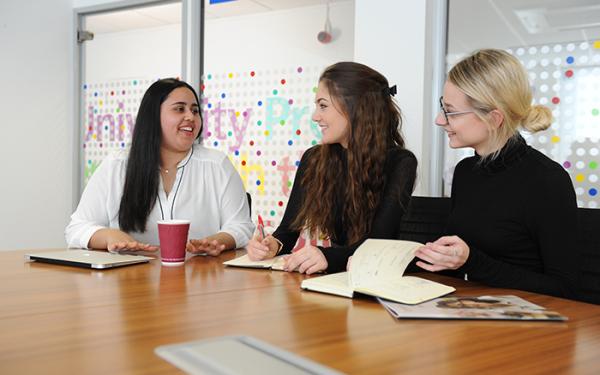 three female colleagues in a meeting room at Cambridge University Press & Assessment's University Printing House building