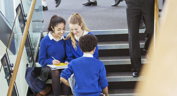 School students working in the school corridor and wearing blue school uniforms.