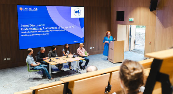 A panel of education experts sit around a table to address questions around AI and assessment to an audience of attendees inside the Hive Lecture Theatre at Headington School