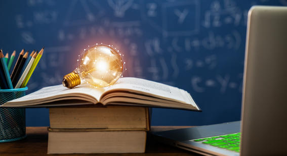 lightbulb on top of books beside a laptop