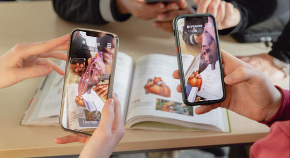 Two people use their phones to access augmented reality content in a textbook