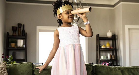 young girl wearing a toy crown looking through a homemade telescope