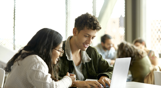 Image of two students looking at laptop screen