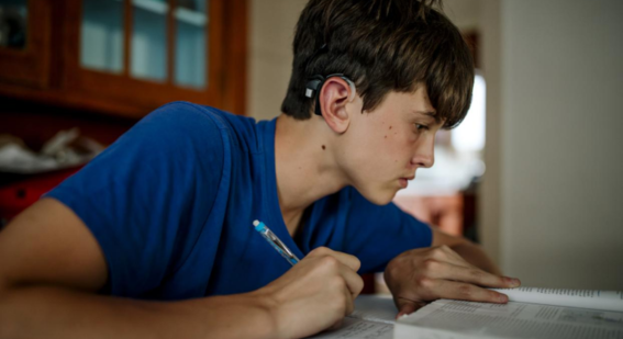 Boy with hearing aid studying 