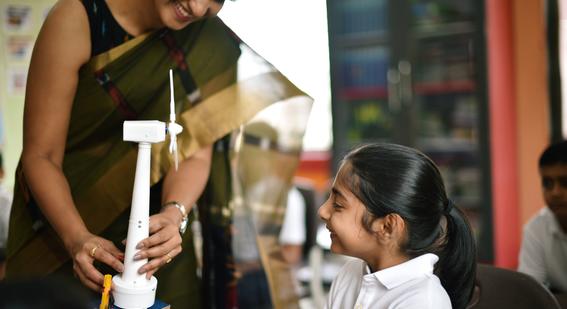 Teacher in India showing a student a model windmill