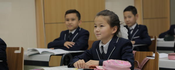 Young children sit at desks in a classroom